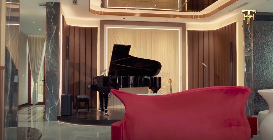 Phòng khách đặt bộ bàn ghế to và cây đàn piano như một sân khấu mini. Ảnh chụp màn hình