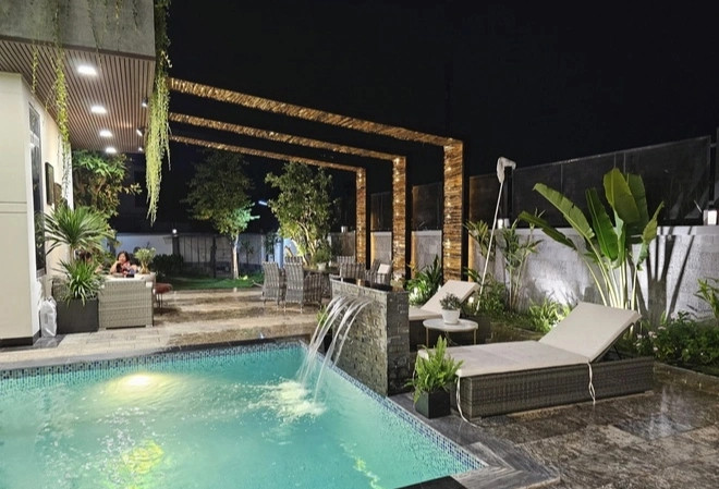Hồ bơi trong khuôn viên biệt thự có thác nước nhỏ và ghế nằm xung quanh, thiết kế chẳng khác khu resort. Ảnh: FBNV