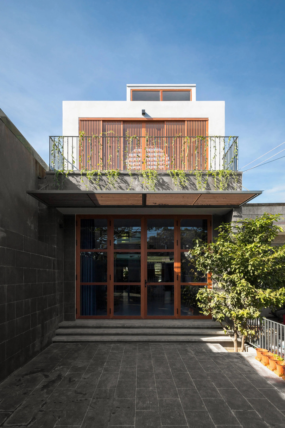 Trong khi đó, tầng 1 có 1 mái hiên dài 2m vươn ra, tạo khoảng đệm che mưa nắng mà không cản trở tầm nhìn.