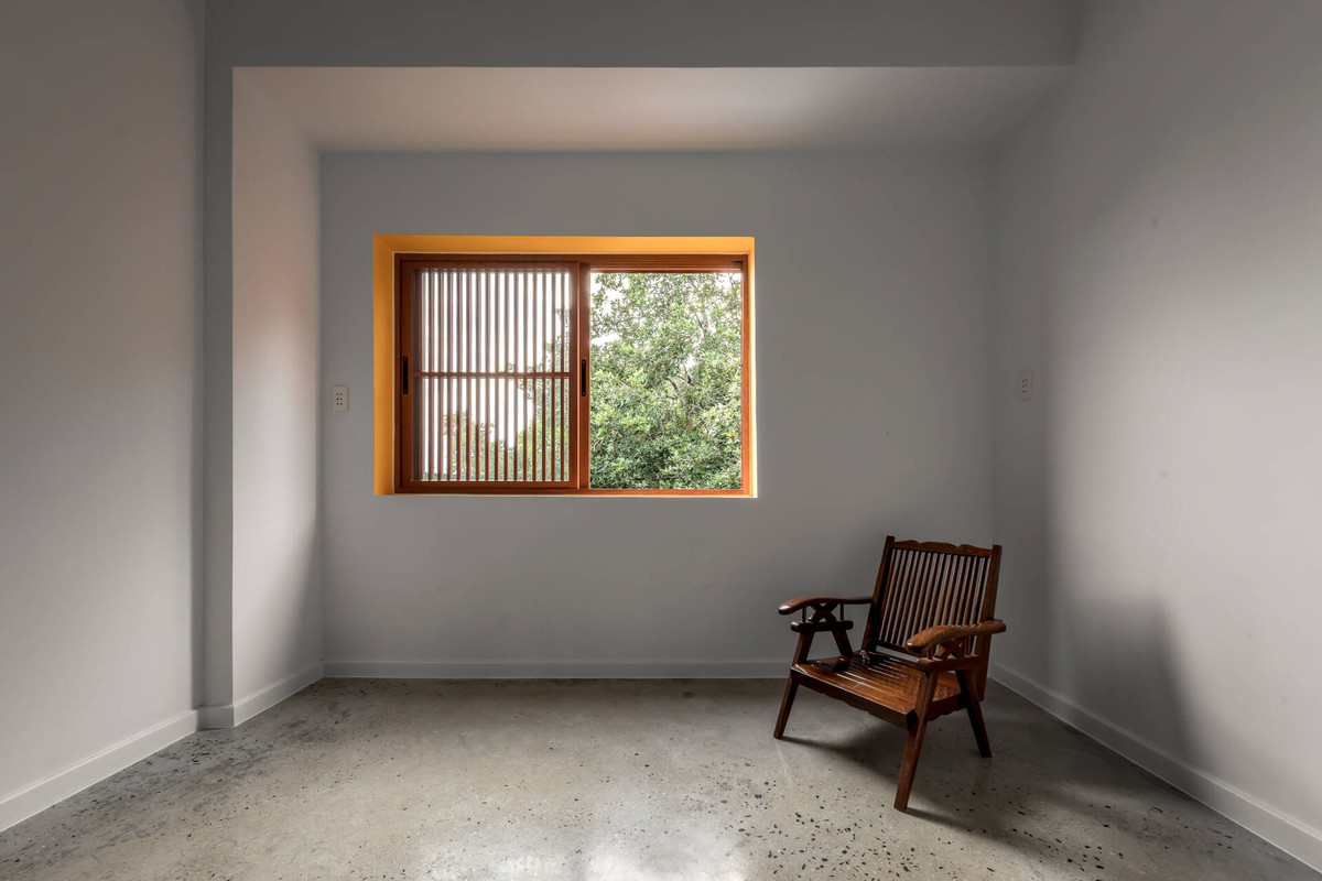 Mặt sau nhà hướng Tây Nam nên cũng khá nóng bức. Vì vậy, kiến trúc sư ưu tiên xây tường đặc để giảm nhiệt. Một số ô cửa sổ nhỏ vẫn được bổ sung, để nhìn ra vườn phía sau xanh mát ra các cây cổ thụ lâu năm.