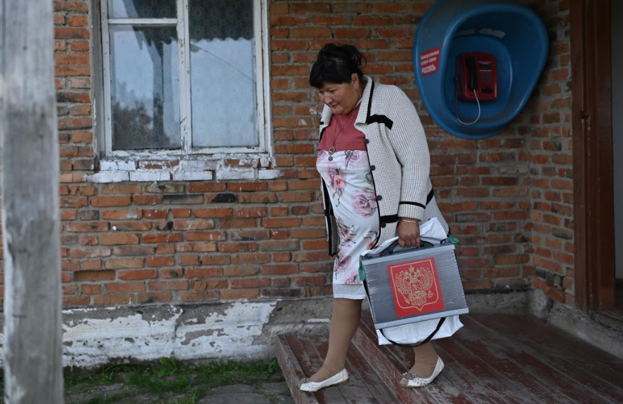 Elmira, một thành viên của Ủy ban bầu cử địa phương, mang theo hòm phiếu di động trong một cuộc bầu cử địa phương.