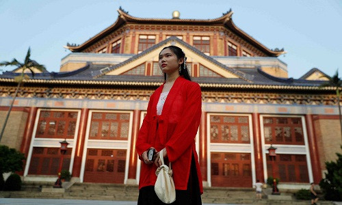 Một cô gái mặc trang phục truyền thống đứng trước hội trường Tưởng niệm Tôn Trung Sơn ở quận Tân Tập, Quảng Châu, Trung Quốc, ngày 7/9. Thành phố cũng chất chứa những mâu thuẫn của Trung Quốc hiện đại. Trong tầm nhìn của khu thương mại trung tâm lấp lánh là phần còn lại của "làng đô thị" của Quảng Châu, như Tiển Thôn.