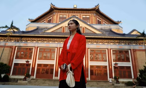 Một cô gái mặc trang phục truyền thống đứng trước hội trường Tưởng niệm Tôn Trung Sơn ở quận Tân Tập, Quảng Châu, Trung Quốc, ngày 7/9. Thành phố cũng chất chứa những mâu thuẫn của Trung Quốc hiện đại. Trong tầm nhìn của khu thương mại trung tâm lấp lánh là phần còn lại của "làng đô thị" của Quảng Châu, như Tiển Thôn.