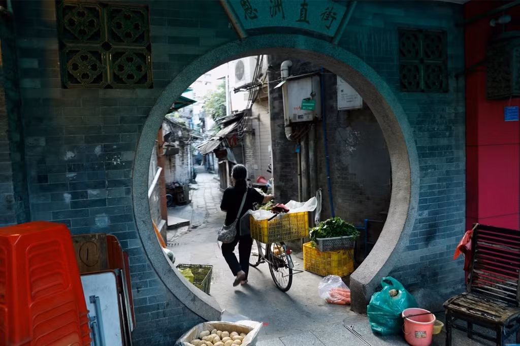 Một phụ nữ dắt xe đạp qua khu phố cổ Lệ Loan ở Quảng Châu, Trung Quốc, ngày 6/9. Quảng Châu, một thành phố 14 triệu dân, không xa lạ gì với sự thay đổi do kinh tế mang lại, và vẫn giữ ý thức mạnh mẽ về bản sắc truyền thống. Khi cảng duy nhất của Trung Quốc mở cửa cho ngoại thương, Quảng Châu được xem là pháo đài của văn hóa và tư tưởng miền Nam Trung Quốc.