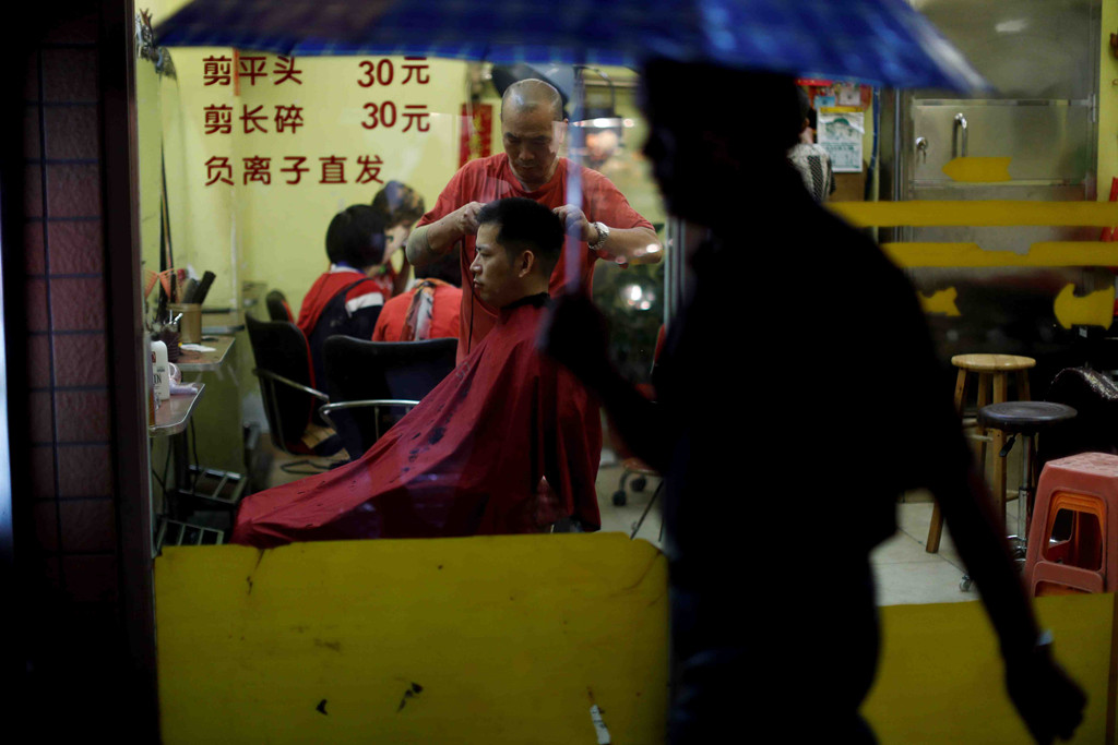 Một khách hàng ngồi trong tiệm cắt tóc ở quận Lệ Loan, Quảng Châu, Trung Quốc, ngày 1/9. Tăng trưởng kinh tế của Quảng Châu đã bắt đầu chậm lại, cùng với phần còn lại của đất nước.