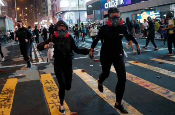 Người biểu tình đeo mặt nạ tháo chạy trên đường phố Hong Kong ngày 27/10.