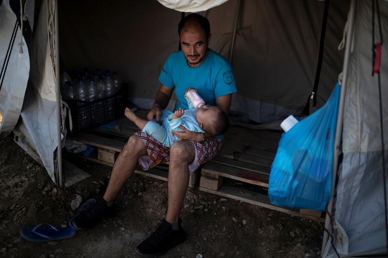 Người đàn ông cho con uống sữa trong khu trại tạm bợ được dựng lên gần trại Moria trên đảo Lesbos ngày 30/9.