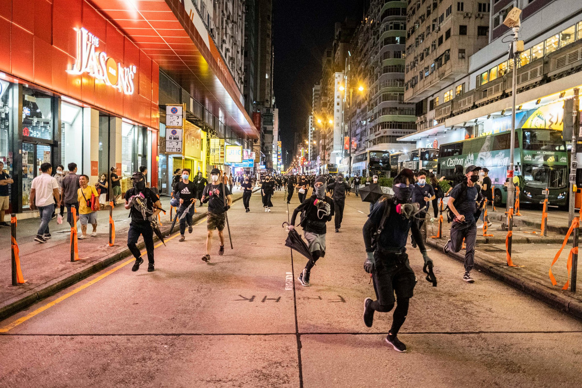 Một số người biểu tình đeo mặt nạ tháo chạy trên đường phố Mong Kok.
