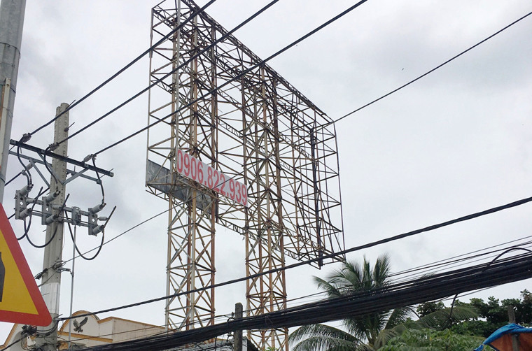 Biển quảng cáo với giàn sắt thép khủng trên QL1A, đoạn qua thị trấn Tân Túc chỉ còn trơ khung, có thể ngã đổ bất cứ lúc nào, trong khi bên dưới là nhiều nhà dân san sát nhau.