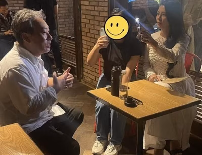 Bùi Lan Hương dùng điện thoại bật đèn flash giúp bạn trai lên hình đẹp hơn khi anh trả lời phỏng vấn. Ảnh: Thương Hiệu Và Pháp Luật.