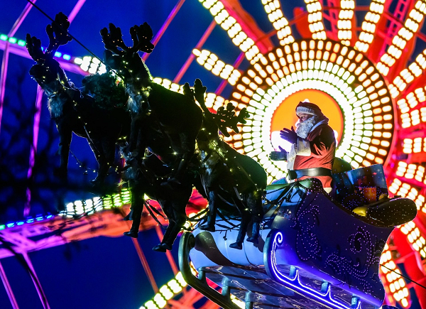 Một nghệ sĩ biểu diễn hóa trang thành ông già Noel cưỡi xe trượt tuyết cùng tuần lộc qua chợ Giáng sinh truyền thống ở Berlin, Đức (Ảnh: AFP).