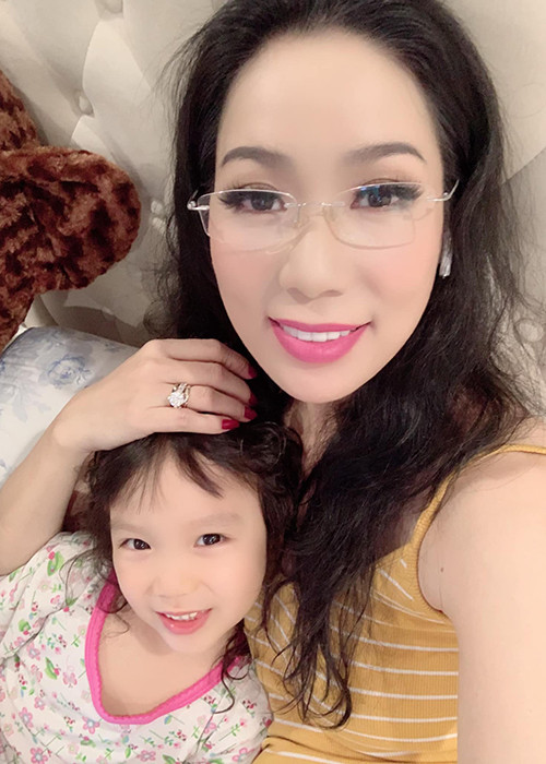 Trịnh Kim Chi đeo kính đọc truyện cho con gái trước khi đi ngủ.