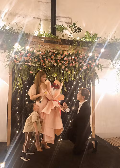 Khi Thu Thủy đứng trên sân khấu, Kin Nguyễn "mất tích" rồi trở lại với bó hoa hồng trên tay. Anh thổ lộ với bạn gái: "Em cho anh biết thế nào là hạnh phúc và mục đích anh sống trên cuộc đời này là gì. Anh đến để bảo vệ 2 mẹ con. Hãy cho anh được bảo vệ 2 mẹ con suốt cuộc đời này khỏi những đớn đau". Ảnh: FBNV