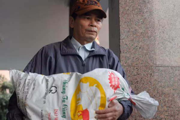 Người đàn ông trung tuổi ôm bao tải nặng lỉnh kỉnh.