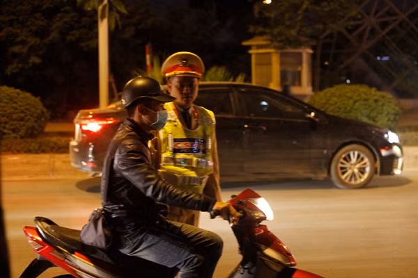 Nam thanh niên đội mũ bảo hiểm không cài quai theo đúng quy định.