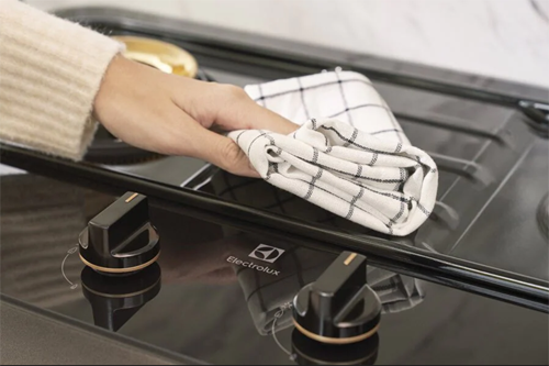 Bước 3, vệ sinh mặt bếp. Trước tiên, dùng khăn ẩm để lau sạch dầu mỡ bám trên mặt bếp. Với những vết bẩn cứng đầu, chị em có thể dùng bàn chải đánh răng, baking soda hoặc rắc muối lên trực tiếp vết bẩn rồi chà mạnh.