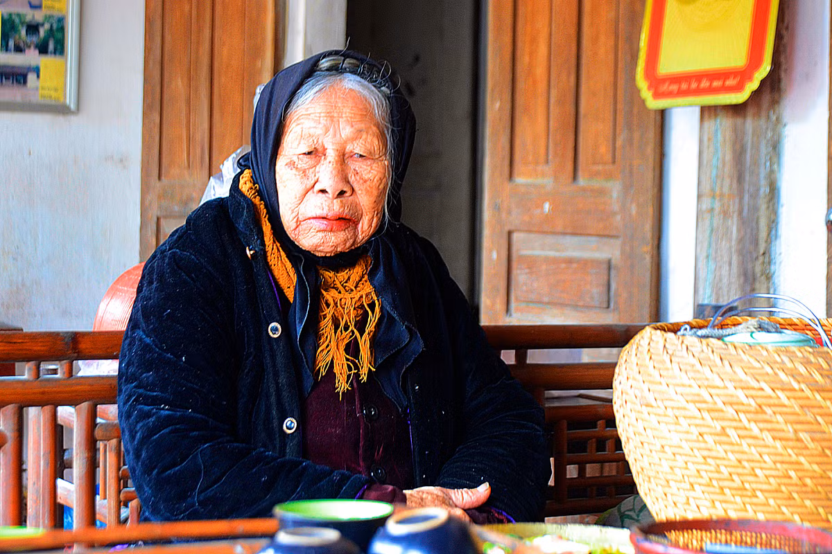 Cụ bà 94 tuổi ngồi tiếp các vị khách du lịch đến tham quan ngôi nhà có 4 thế hệ này.