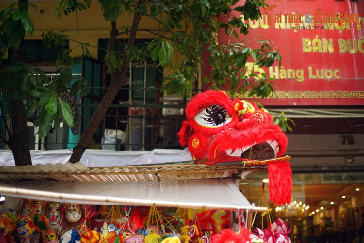 Chiếc đầu lân đỏ rực "ngắm" dòng người qua lại từ mái che của một gian hàng trên phố Hàng Lược.