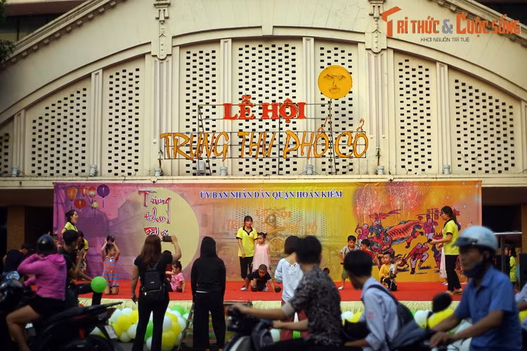 Nhiều du khách ghé xem các em nhỏ diễn tập cho lễ hội Trung thu phố cổ ở sân khấu phía trước chợ Đồng Xuân.