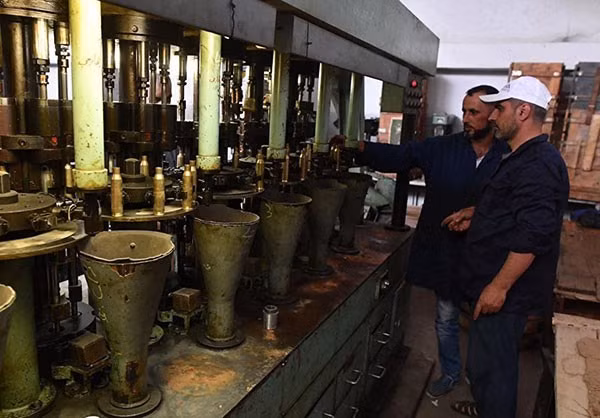 Hai người công nhân đang trao đổi trong nhà máy sản xuất đạn dược ở Hama. Ảnh: FNA. 