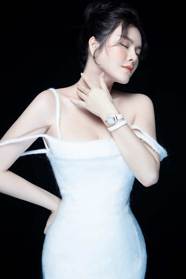 Nữ diễn viên "Kiều nữ và đại gia" diện trang phục trắng tinh khôi, đeo đồng hồ đính kim cương, trang điểm nhẹ nhàng.