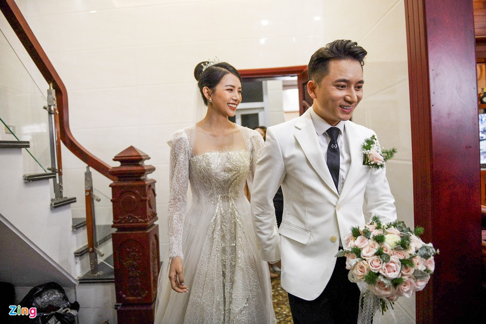 Sau thánh lễ hôn phối diễn ra tại nhà thờ xứ Vạn Phần, lễ cưới chính thức của nhạc sĩ Phan Mạnh Quỳnh và cô dâu Huỳnh Khánh Vy tổ chức tại quảng trường vào ngày 17/4. Trước giờ G, chú rể dắt tay người bạn đời bước ra từ nhà. Nam nhạc sĩ diện suit trắng lịch lãm. Khánh Vy gợi cảm trong bộ đầm cưới cúp ngực.