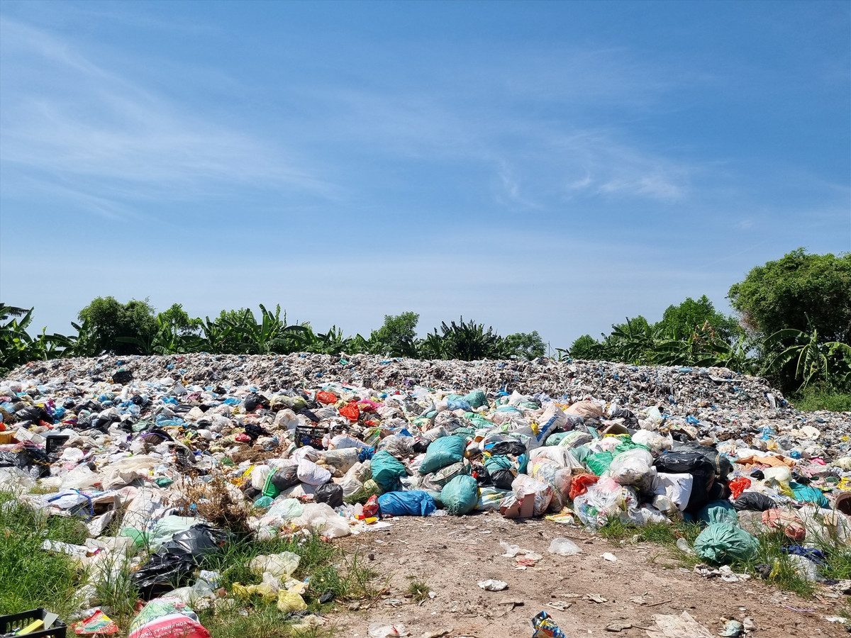  Bãi rác lộ thiên nằm cạnh khu dân cư: Vừa qua, Báo Lao Động nhận được phản ánh của người dân liên quan đến việc bãi xử lý rác của xã Nghĩa Bình (huyện Nghĩa Hưng, tỉnh Nam Định) có vị trí ngay gần khu dân cư, chỉ cách khoảng 300m, thường xuyên bốc mùi hôi thối, gây ô nhiễm. "Chúng tôi sống gần bãi rác này, gió theo chiều nào người dân ở khu đó phải chịu khổ. Nhà chúng tôi phải thường xuyên phun thuốc ruồi, hôm nào quên không phun là ruồi nhiều như đỗ đen. Đợt vừa rồi bãi rác còn cháy âm ỉ suốt 2 tháng trời. Không biết xử lý chôn lấp kiểu gì mà rác cứ thành đống, đứng ngoài cũng nhìn thấy" - ông Lưu Công Ích (66 tuổi; người dân thôn Thịnh Phú, xã Nghĩa Bình, huyện Nghĩa Hưng) nói. (Ảnh Báo Lao Động)