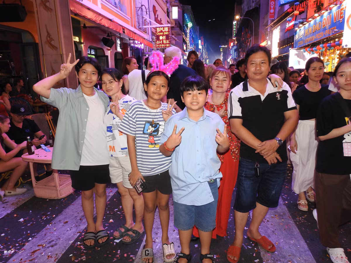 Nhóm gia đình tại TP HCM tranh thủ check -in khi pháo hoa rực sáng bầu trời tại khu phố Tây Bùi Viện. (Ảnh: Bảo Giang)