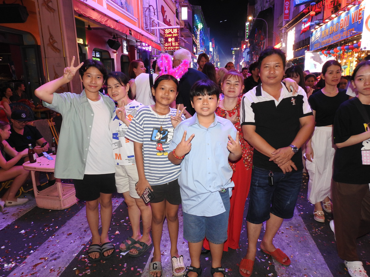 Nhóm gia đình tại TP HCM tranh thủ check -in khi pháo hoa rực sáng bầu trời tại khu phố Tây Bùi Viện. (Ảnh: Bảo Giang)