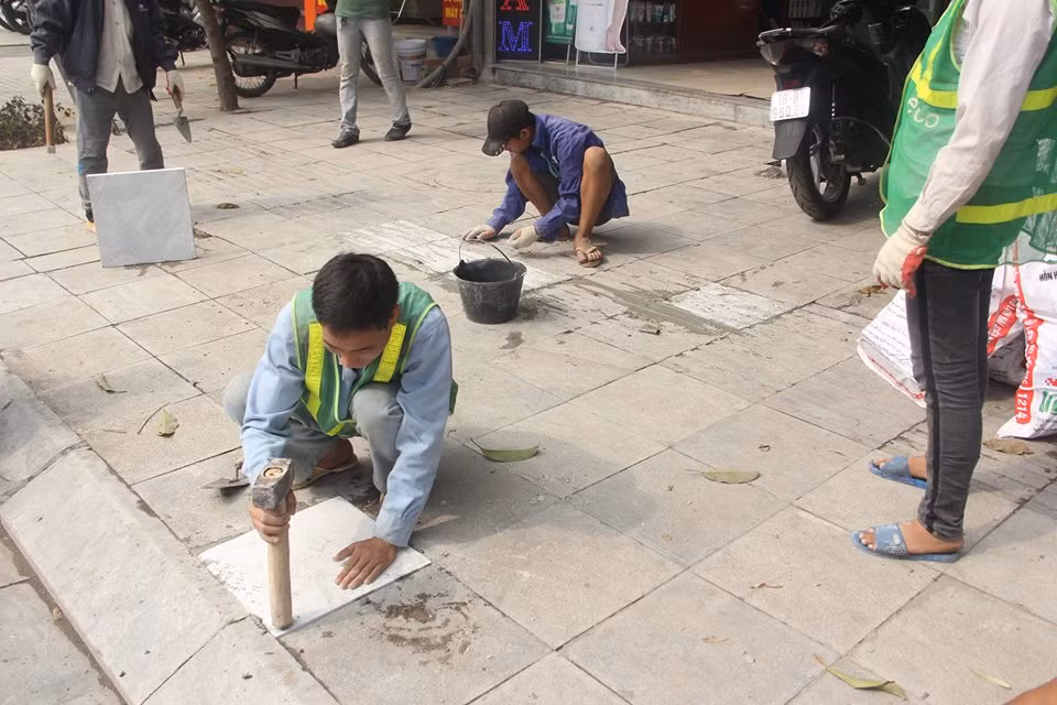 Công nhân đang "vá" đá vỉa hè mới đưa vào sử dụng đã hư hỏng.