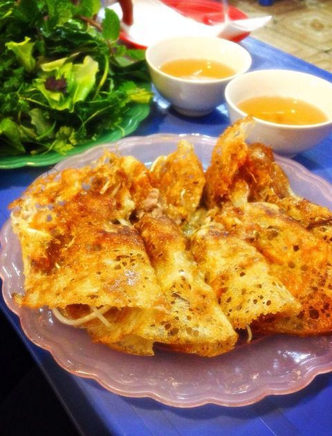 Bánh xèo 77A Đại Cồ Việt. Đây là quán đông và thực khách phải chờ lâu bởi chỉ có 2 ông bà chủ quán làm, không mướn thêm người. Ông làm bánh, bà chạy bàn. Tuy mệt nhưng trên khuôn mặt của 2 người ấy vẫn toát lên niềm vui. Bánh ở đây ngon tuyệt đúng điệu bánh xèo, tôm cũng to và thịt nhiều. Bánh giòn vỏ ngoài, thơm thơm mùi của tôm và thịt. Ăn kèm với bánh đa và rau sống ngon tuyệt vời. Mỗi cái bánh có giá 13.000 đồng. (Ảnh: Lozi).