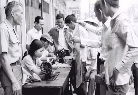 Vỡ òa trước niềm vui thống nhất đất nước, các hiệu may trong Thành phố Đà Nẵng đưa máy khâu ra hè phố may cờ cách mạng cho nhân dân treo trong ngày giải phóng, từ chối nhận tiền công. Ảnh: Nhà báo Đinh Quang Thành.