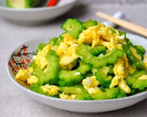 Món phụ 2: Mướp đắng xào trứng. Mướp đắng có giá trị chất dinh dưỡng rất lớn, đặc biệt là tác dụng giải độc gan, giải nhiệt cho cơ thể trong những ngày hè oi bức. Cách chế biến món ăn này cũng rất đơn giản. Đầu tiên, đập trứng ra bát rồi đánh nhuyễn. Sau đó, bạn thái mướp đắng thành từng lát mỏng. Đặt chảo lên bếp, cho dầu ăn đảo cùng với mướp đắng cho chín với chút muối nêm nếm cho vừa miệng, rồi cho ra bát. Đổ trứng vào chảo đảo liên tục cho chín rồi đổ thêm mướp đắng vào xào cùng lần nữa là được.