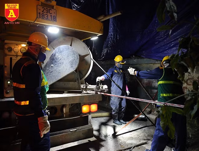 Các công nhân chia ra thành từng nhóm quanh nhà máy Rạng Đông cậy các nắp cống để tiến hành hút, nạo vét bùn