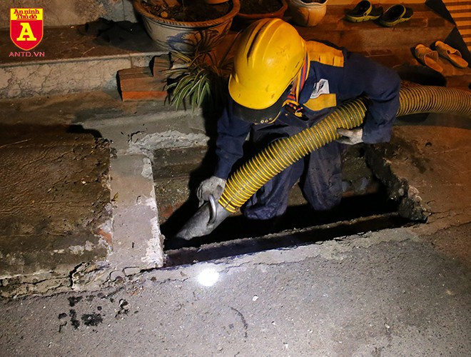 Công nhân xuống hẳn hố ga để đưa ống hút vào sâu hơn