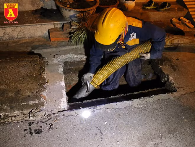 Công nhân xuống hẳn hố ga để đưa ống hút vào sâu hơn