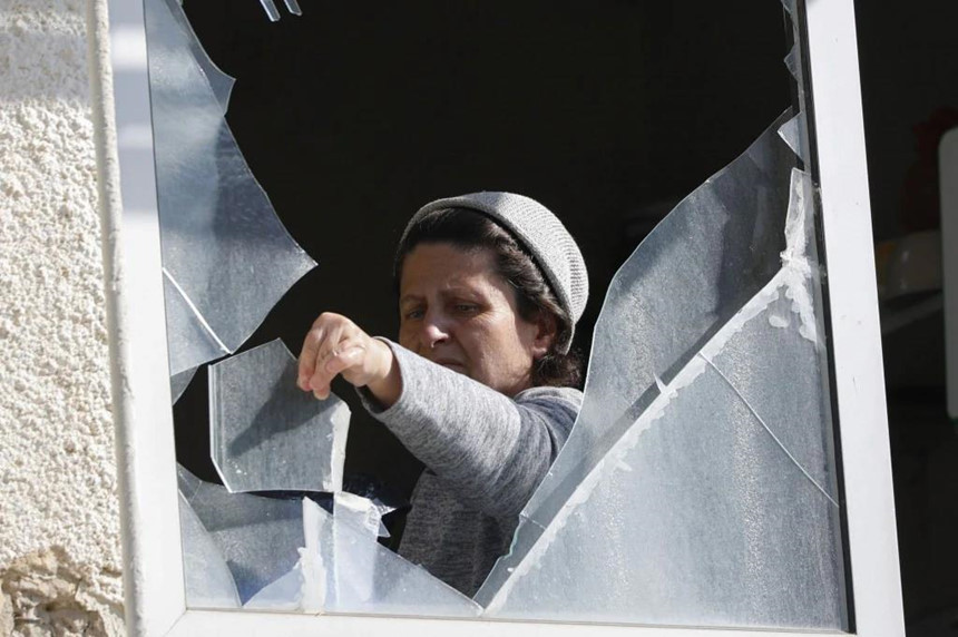 Một phụ nữ Israel tại thị tr tháo bỏ những mảnh kính vỡ từ cửa số nhà mình sau khi nó bị phá hỏng bởi rocket từ dải Gaza. Ảnh: AFP.