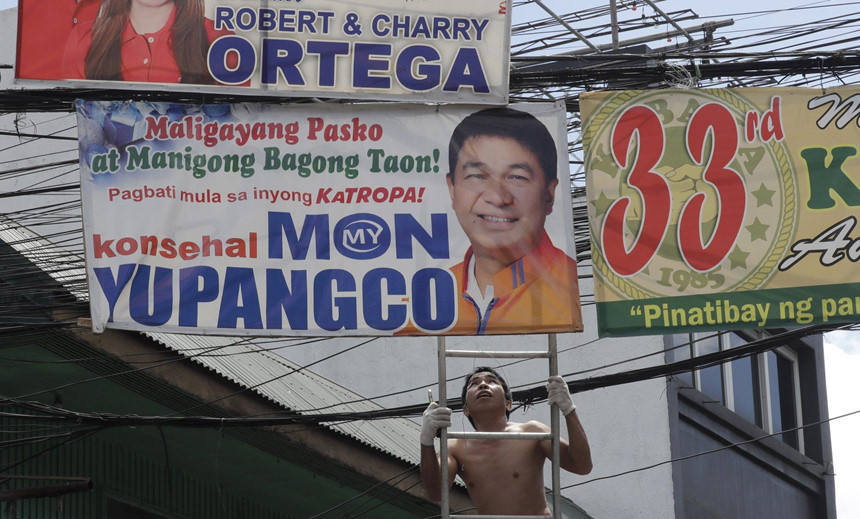 Nhân viên tháo dỡ một tấm băng rôn bầu cử được treo trái quy định của Ủy ban Bầu cử Philippines. Ảnh: AP.