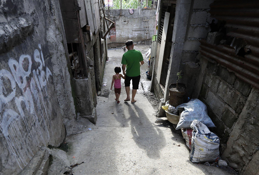 Anh Randy Delos Santos đi bộ cùng con gái cạnh khu vực mà người cháu trai 17 tuổi của anh bị cảnh sát giết trong một vụ bắt giữ ma túy ở Quezon City. Ba cảnh sát bị buộc tội giết hại Kian Lloyd Delos Santos mà không có bằng chứng. Ảnh: AP.