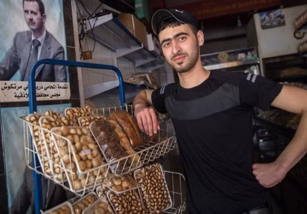 Nam thanh niên chụp ảnh khi đứng cạnh kệ bày bánh.