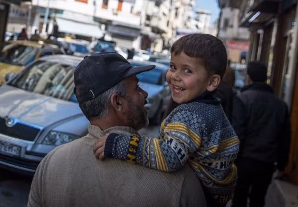 Bé trai ngoảnh mặt lại và nở nụ cười rạng rỡ trước ống kính.