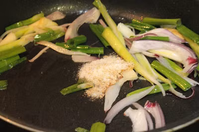 Khi chiên xong đậu bạn cho hành tây, hành lá vào xào khoảng 3 phút. Trộn một thìa nhỏ muối, nửa thìa nhỏ hạt nêm, một ít hạt tiêu vào bát nhỏ rồi trút vào chảo. Ảnh: Ngôi sao.