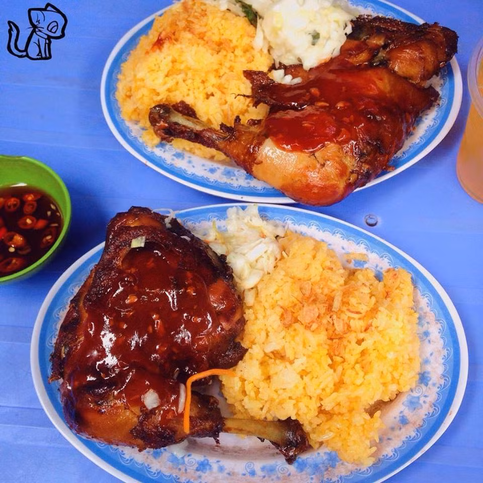 Cơm gà chiên: Đây lại là món ăn trưa yêu thích của teen Hà Nội. Một phần cơm gồm có cơm nấu nước dùng gà dẻo, béo ăn kèm với chiếc đùi gà liên bả chiên mắm phủ sốt và rau dưa góp. Ảnh: Monngonmoingay.