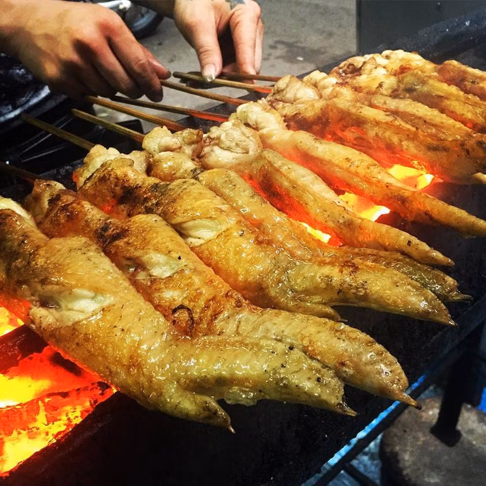 Cánh gà nướng than hoa: Để làm nên món gà này được chế biến khá đơn giản để giữ mùi thơm ngon tự nhiên của thịt gà. Khi chế biến người ta thường ướp cánh gà sau đó xiên que rồi nướng chín vàng trên than hoa. Món ăn thường được bán vào buổi chiều và tối ở các khu phố Gầm Cầu, phố chân gà nướng. Ảnh: Monngonmoingay.