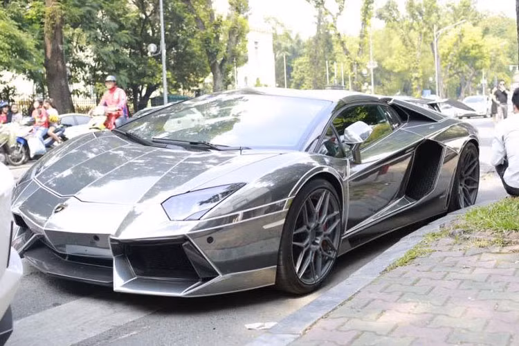 Theo tìm hiểu, chiếc Lamborghini Aventador mui trần màu crôm đen cùng các sọc dạ quang màu trắng nổi bật mới được một doanh nhân Hà Nội chuyên kinh doanh lĩnh vực đồng hồ và điện thoại cao cấp mua lại.