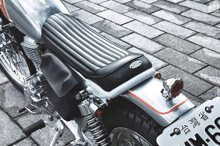 Bên phải khung sườn là tấm biển số trang trí được làm bằng tay với công tắc xe ngay cạnh, trong khi đối diện có túi da để phụ tùng.