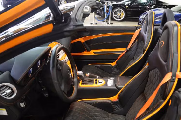 Bên trong khoang lái của siêu xe Mercedes-Benz SLR McLaren Edition Roadster bao gồm cặp ghế ngồi thể thao bọc da cao cấp màu đen kết hợp cùng sọc cam, thành cửa bọc da Alcantara màu đen kim cương, bệ cửa bằng sợi carbon
