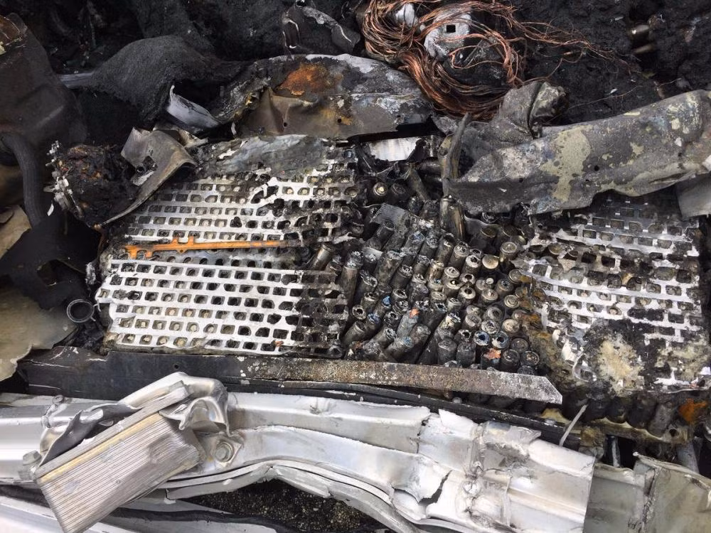 Va chạm mạnh đã khiến chiếc xe bốc cháy. Trong ảnh là cụm pin dưới sàn xe nhôi ra hoàn toàn.