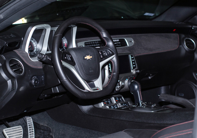 Nội thất tông đen chủ đạo với đường chỉ khâu màu đỏ tương phản, bộ bàn đạp bằng nhôm và hiển thị thông tin trên kính lái HUD.