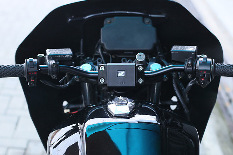 Ghi đông được hạ thấp ngang bằng với bình xăng và thẳng mang phong cách tracker, gắn trên nó là bọc tay lái Biltwell và cụm công tắc mới. Đầu đèn hình chữ nhật đặc trưng của dòng CBX cảnh sát được bố trí lại.